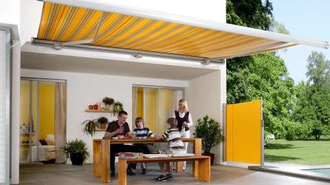 gelbe markilux 6000 Markise über einer Terrasse, auf der eine Familie sitzt