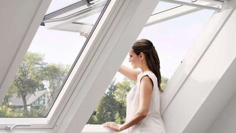 Frau öffnet ein Klapp-Schwing-Fenster im Dach