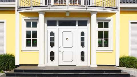 weiße Haustür im gelben Haus mit Säulen und Treppenstufen