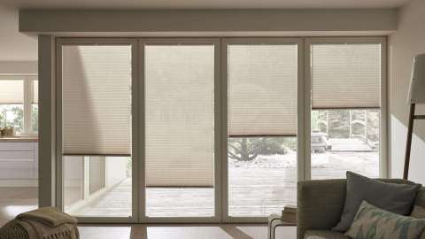 vier bodentiefe Fenster mit innenliegendem Sonnenschutz in einem Wohnzimmer