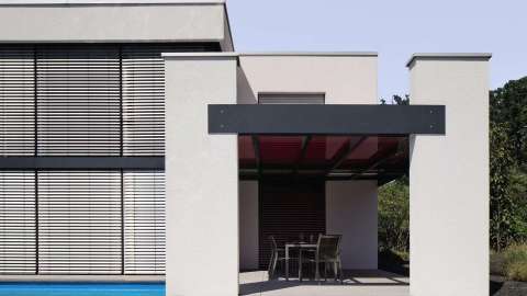 Modernes Haus mit Terrassendach und roter Aufglasmarkise