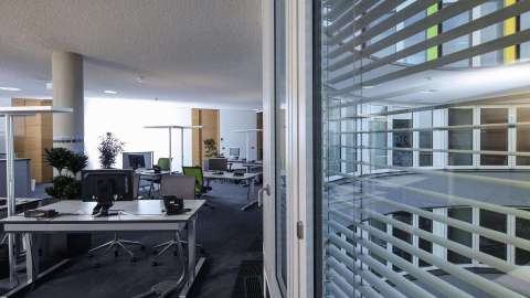 Blick in ein offenes Großraumbüro mit Fenster mit Raffstore an der rechten Seite