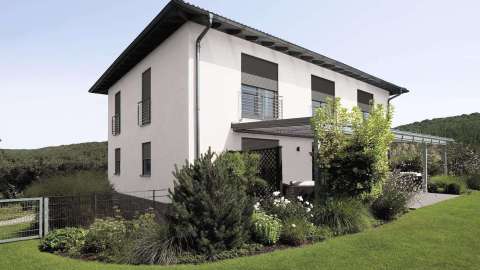 modernes weißes Wohnhaus mit Terrassendach und großem Garten