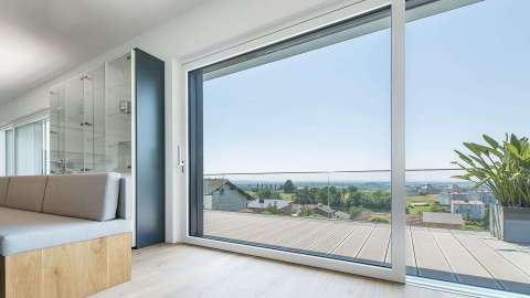 Innenansicht eines bodentiefen Kunststoff-Aluminium-Fensters mit Blick auf einen Balkon