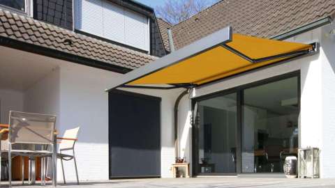 gelbe Markise über zwei großen Terrassenfenster in einer Hausecke