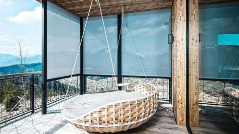 Terrasse, einseitig verglast mit Textilscreens und rundem Sessel zum Entspannen