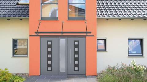 graues Vordach über grauer doppel-flügeliger Haustür in einem gelb-orangen Haus