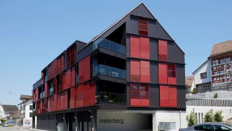 großes Haus mit roten Loggia-Schiebeläden an der Fassade