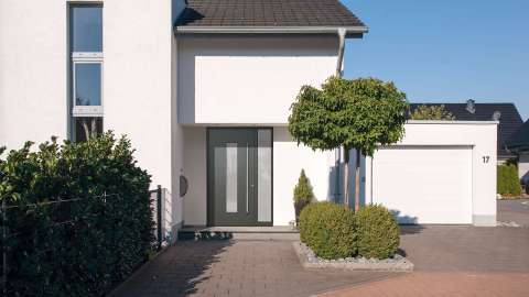 hellgraue Haustüre mit Glaselement auf der rechten Seite in einem weißen Haus