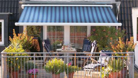 blaue markilux 1600 Markise über einer Terrasse mit Esstisch und Stühlen