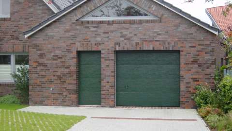 grünes Garagentor mit passender Nebeneingangstür in rotem Klicker