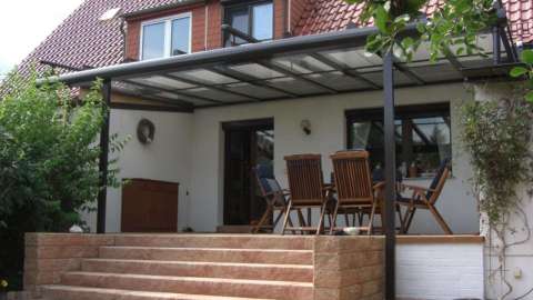 Terrassendach an einem Wohnhaus mit Treppenaufgang zur Terrasse mit Sonnenschutz