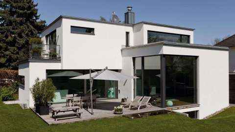Modernes Flachdachhaus mit großer Terrasse mit Liegestühlen und Sonnenschirm