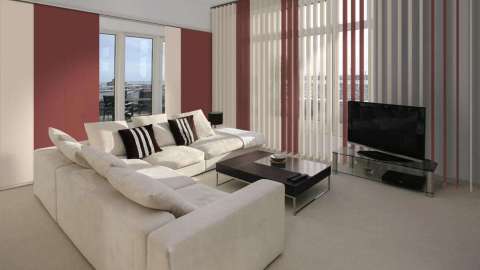 Wohnzimmer mit großem Sofa und weiß-orangen Vertikal-Jalousien