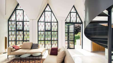 Innenansicht eines Wohnzimmers mit dreieckigen Buntglasfenstern und geöffneter Glas-Faltwand