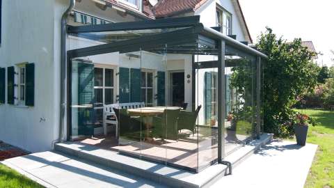 Glashaus mit Esstisch an einem Wohnhaus