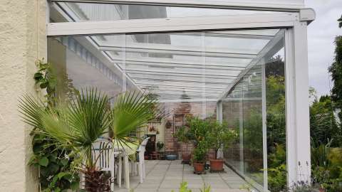 Seitenansicht eines weißen Glashauses mit Pflanzen im Inneren