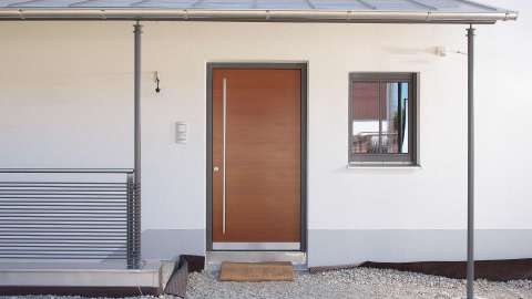 Haustür aus Lärchen-Holz in weißer Fassade mit Vordach