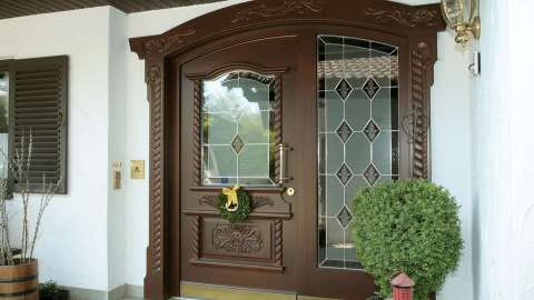 braue Haustür mit Ornamenten und Glaselement auf der rechts Seite in weißer Fassade