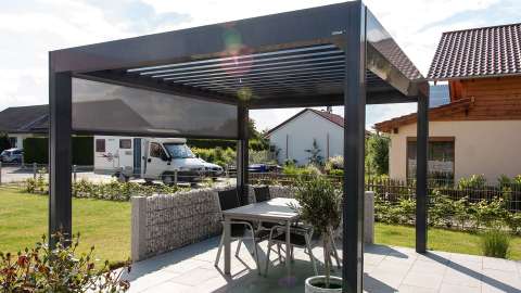 freistehendes Lamellendach Camargue auf einer Terrasse mit geöffneten Lamellen und seitlichem Sicht- und Sonnenschutz