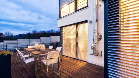 Terrasse mit Esstisch an einem Haus mit Aufsatzraffstoren vor den Fenstern
