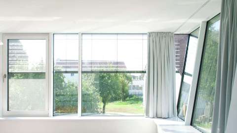 Raum mit Aluminium-Fenstern von Gugelfuss mit grünen Gardinen