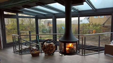 Wintergarten-Dachsystem mit freihängendem Kamin und Blick in den Garten