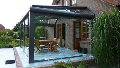 Glashaus auf einer großen Terrasse mit Esstisch an einem Wohnhaus