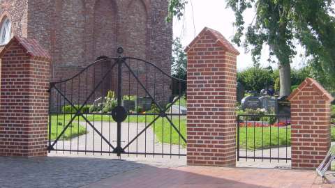 Kirchentor vor einem Friedhof mit Kapelle