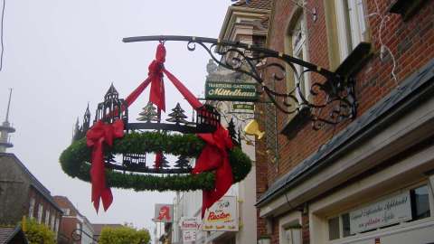 Weihnachtskranz mit Norder Stadtmotiven hängt an einer Fassade in der Altstadt