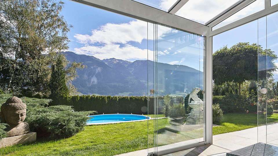 Glashaus mit geöffnetem cero-Schiebesystem mit Blick in die Berge