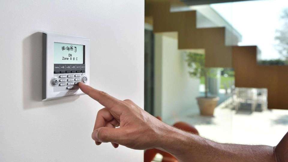 Hand bedient ein Smart Home Steuergerät in der Wand