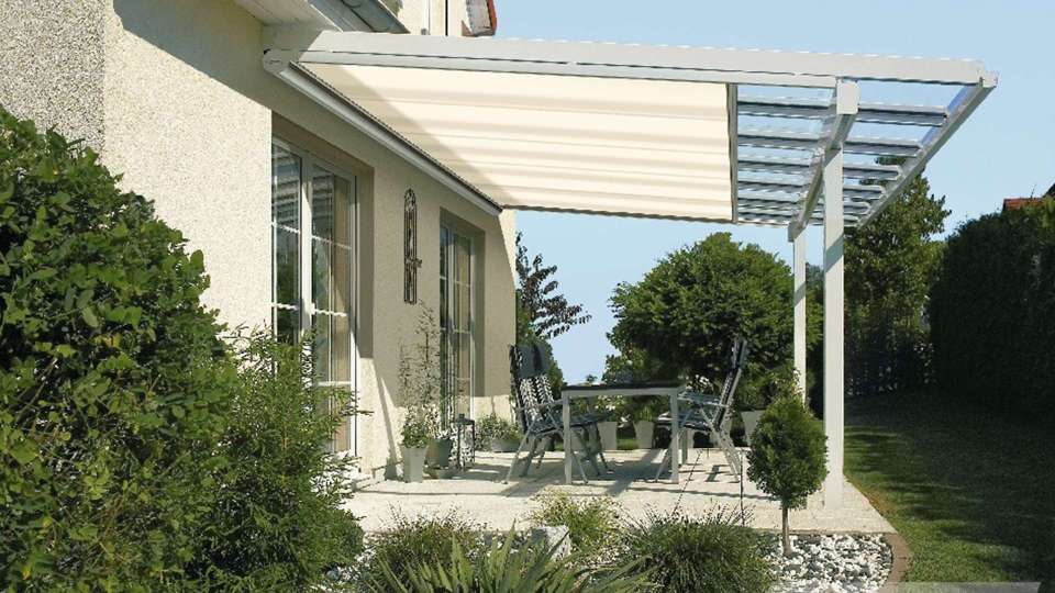 Terrassendach mit Unterglas-Markise an einem Wohnhaus mit grünem Garten