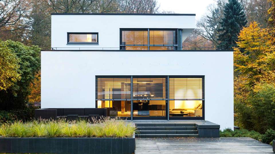 modernes Flachdach-Haus mit Raffstoren vor den Fenstern im Grünen