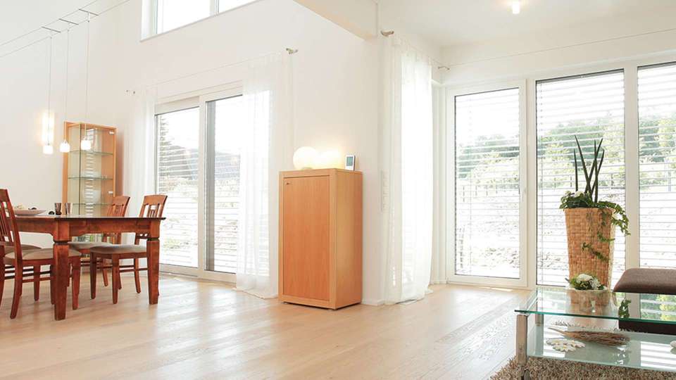helles Wohnzimmer mit bodentiefen Holzfenstern mit Raffstoren